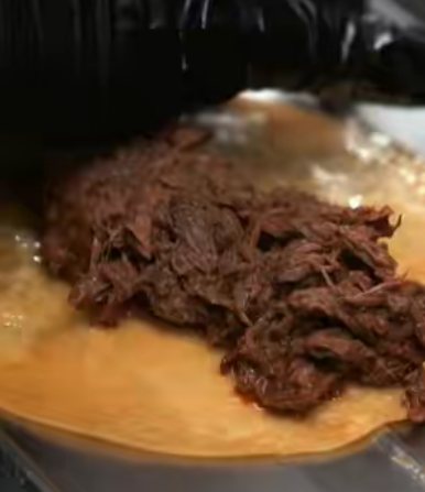 Slow-cooked shredded beef birria on a tortilla